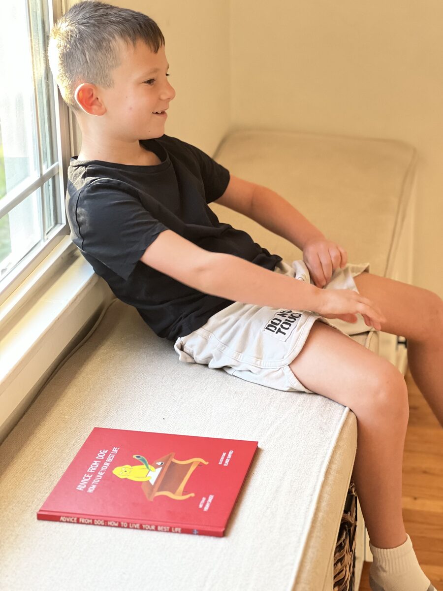 A child beside the window with an Advice From Dog book